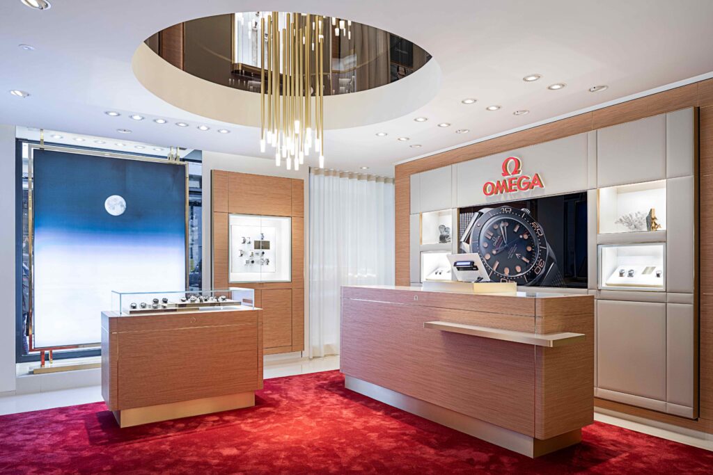 Ground floor of the Omega's restyled boutique in Milan. Cream walls, red carpets and showing decks 